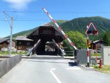 BÜ mit kurzen Schranken an einer überdachten Brücke unweit Bf Reckingen