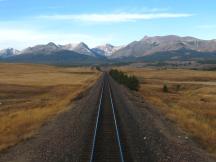 Prärielandschaft neben der Strecke und Ausblick auf die Rocky Mountains